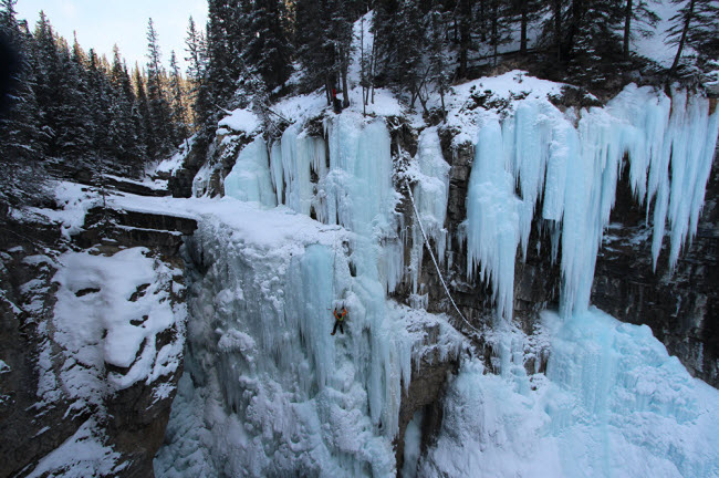 Một người leo núi chinh phục thác nước đóng băng trong vườn quốc gia Banff ở Alberta, Canada.