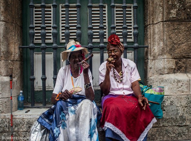 2 phụ nữ địa phương Cuba mặc áo truyền thống đang hút xì gà. Bà cụ 92 tuổi bên trái cho biết bà hút xì gà mỗi ngày và rất khỏe mạnh.