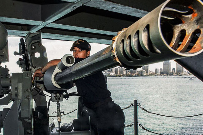 Nữ binh sĩ bảo dưỡng khẩu súng máy Mark 38-25 mm trên tàu sân bay USS Carl Vinson tại cảng ở thành phố San Diego.