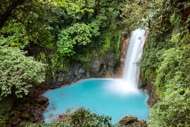 Nước từ thác Rio Celeste waterfall đổ xuống hồ nước xanh trong vườn quốc gia núi lửa Tenorio, Costa Rica.