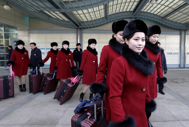 Khi di chuyển đến Hàn Quốc, các thành viên chọn trang phục màu đỏ nổi bật cùng chiếc mũ lông màu đen.