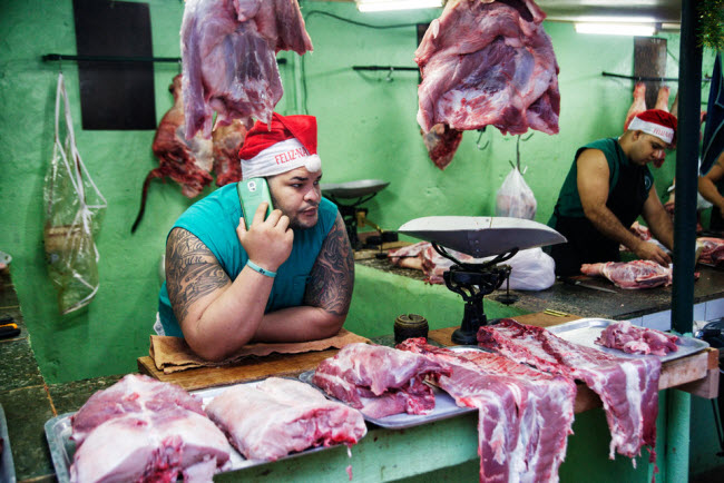 Người bán thịt nói chuyện qua điện thoại di động tại một khu chợ ở Havana, Cuba. Ảnh: Alexey Kharitonov