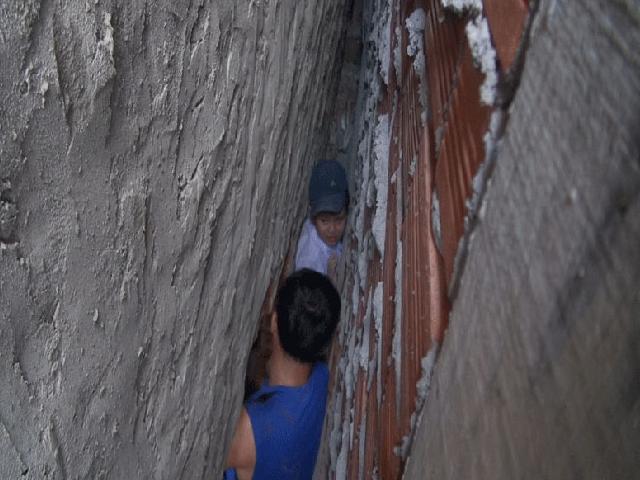Bé trai 7 tuổi rượt đuổi mèo mắc kẹt sâu giữa hai tường nhà