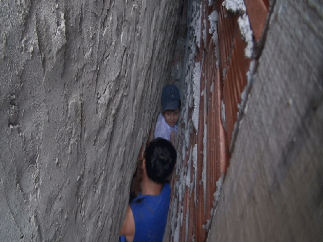 Bé trai 7 tuổi rượt đuổi mèo mắc kẹt sâu giữa hai tường nhà - 1