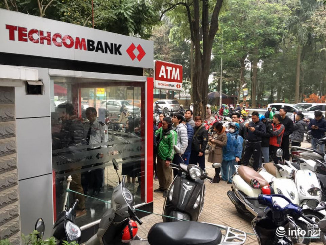 Bên ngoài, dòng người kiên nhẫn xếp hàng chờ đến lượt rút tiền tại ATM.