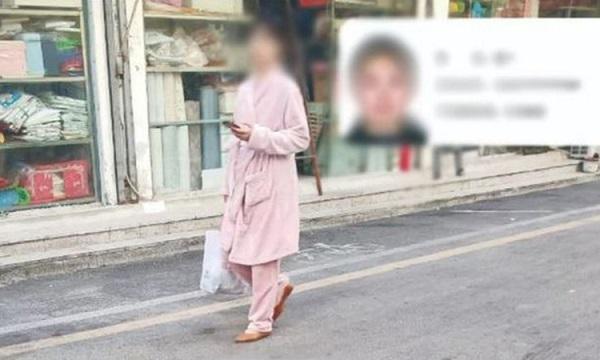 Một người dân mặc đồ ngủ ra đường bị bêu tên - Ảnh: BBC