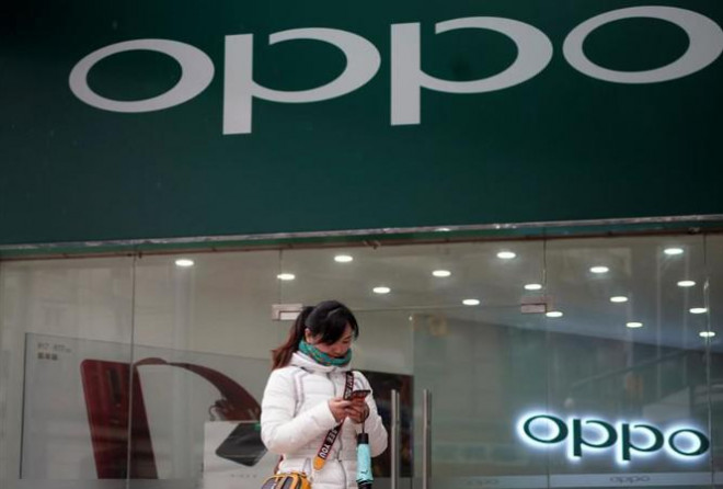 Một phụ nữ đứng trước một cửa hàng của hãng điện thoại Oppo. Ảnh: Reuters
