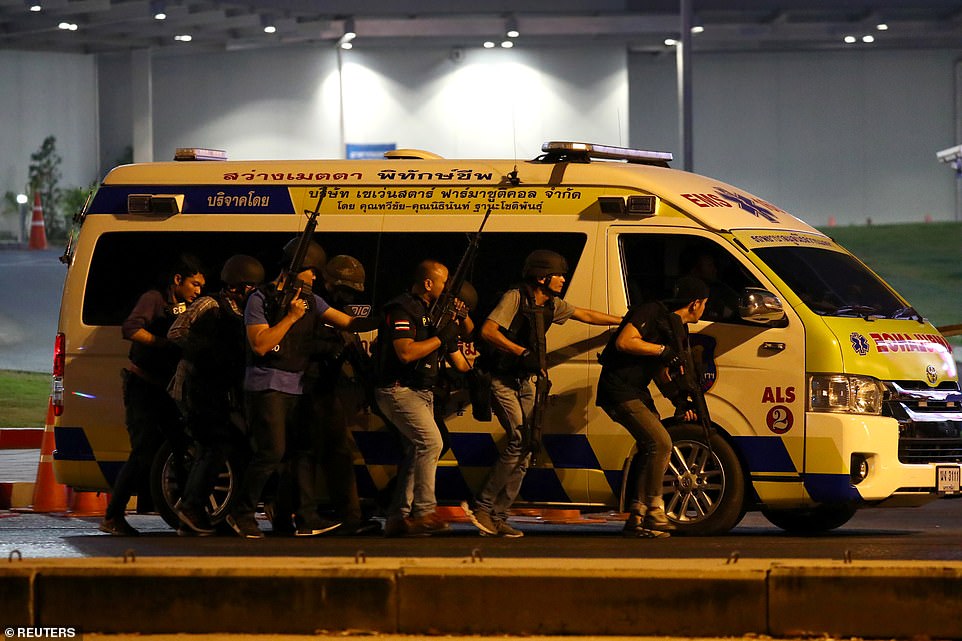 Lực lượng an ninh Thái Lan nấp sau một chiếc xe cứu thương để tránh bị trúng đạn khi truy đuổi quân nhân xả súng tối 8/2. Ảnh Reuters