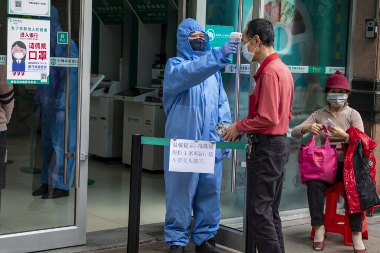 Kiểm tra thân nhiệt người bước vào một ngân hàng ở Quảng Châu ngày 24.2.2020.