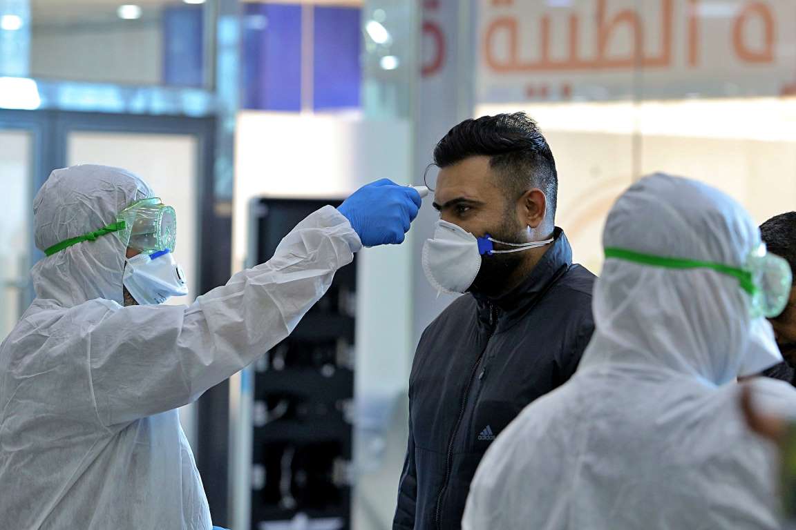 Nhân viên y tế kiểm tra thân nhiệt hành khách từ Iran tại sân bay Najaf, Iraq (Ảnh: AP)