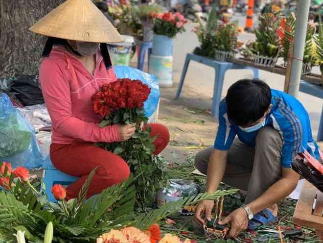 Người phụ nữ tranh thủ kết những lẵng hoa hồng