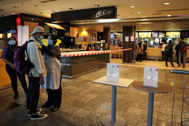 Nhân viên tại cửa hàng McDonald kiểm tra thân nhiệt của khách trước khi vào.