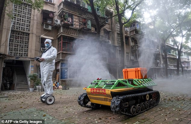 Nhân viên y tế Trung Quốc điều khiển xe tăng phun thuốc khử trùng trên đường phố (ảnh: Daily Mail)