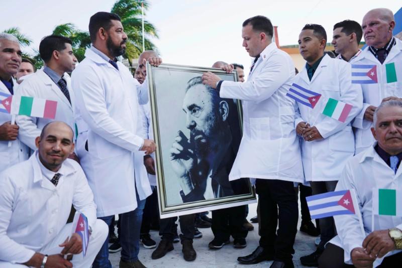 Các bác sĩ Cuba mang theo hình ảnh của cố Chủ tịch Cuba – lãnh tụ Fidel Castro, trong buổi lễ chia tay để lên đường sang Italia chống dịch (ảnh: Reuters)