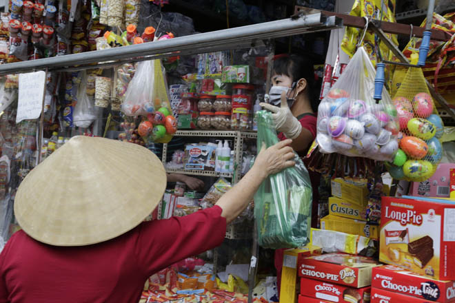 Chủ cửa hàng đưa đồ cho khách qua vách ngăn.