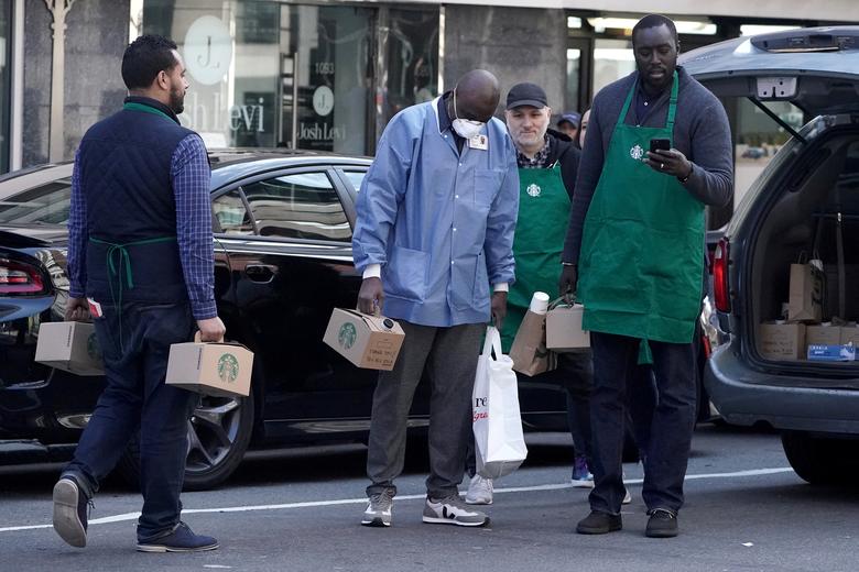 Một nhân viên y tế nhận được hộp cà phê miễn phí từ các nhân viên của Starbucks ở Manhattan, New York. Các nhân viên y tế và y bác sĩ tại Mỹ đang nhận được rất nhiều tình cảm của người dân (ảnh: Reuters)