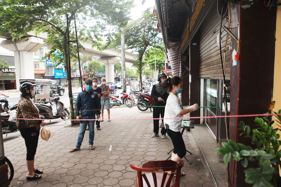 Sáng nay, một cửa hàng bán bánh bao, bánh mì trên phố Hào Nam (quận Đống Đa) đã chăng dây để nhân viên giữ khoảng cách với khách hàng.