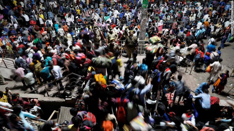 Nhân viên an ninh bất lực, không thể kiểm soát được đám đông lao động nhập cư Ấn Độ tại một trạm xe bus lớn ở thành phố Ghaziabad, bang Uttar Pradesh hôm 28/3. Ảnh: Reuters