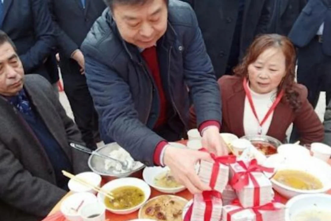 Ông Zheng chia các bó tiền cho mọi người (nguồn: SCMP)