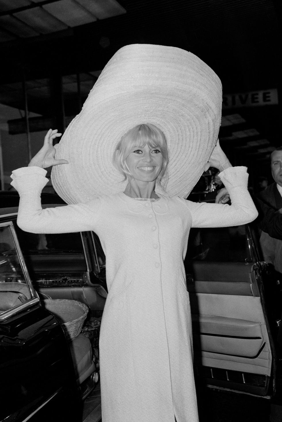 Brigitte Bardot, 1965: Đến sân bay Orly của Paris sau chuyến đi đến Mexico, tất cả đều được tỏa sáng bởi nụ cười của Bardot. Nhưng có điều gì đó cho chúng ta biết những người bạn ngồi cùng ghế của cô ấy ít vui mừng hơn về sự lựa chọn của cô ấy về chiếc mũ? &nbsp;