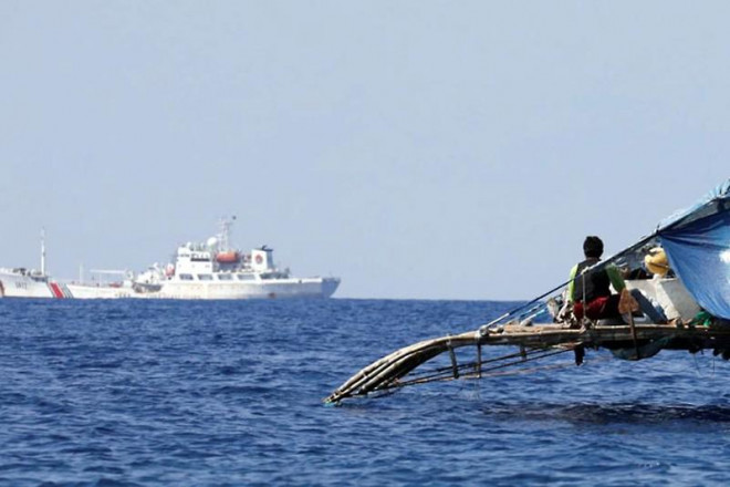 Ngư dân Philippines quan sát một tàu hải cảnh TQ di chuyển trong khu vực bãi cạn Scarborough. Ảnh: REUTERS