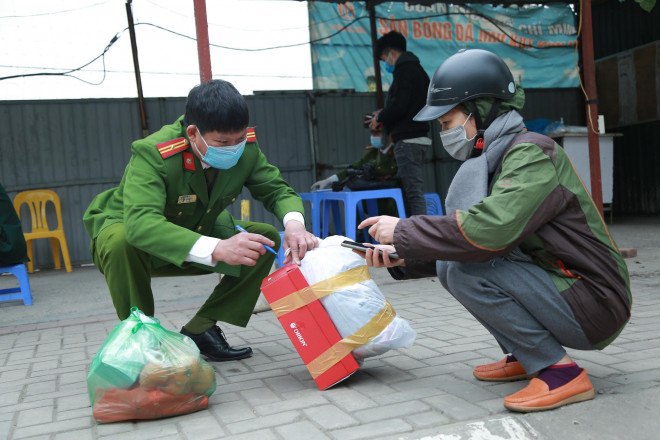 Lực lượng chức năng hỗ trợ phụ huynh gói gọn đồ để chuẩn bị "tiếp tế" vào phía bên trong khu vực cách ly.