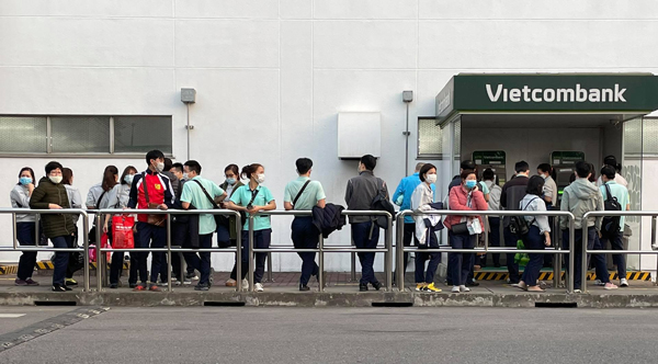 Trong giờ tan tầm, mọi người xếp hàng dài để chờ rút tiền tại cây ATM tại khu công nghiệp Thăng Long (Đông Anh, Hà Nội).