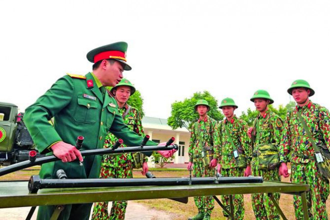 Thiếu tá Trịnh Hải Nam (bên trái) hướng dẫn chiến sĩ trong Tiểu đoàn về nguyên lý hoạt động của giàn phun khử trùng được chế tạo từ ý tưởng của anh - ẢNH: NGUYỄN MINH