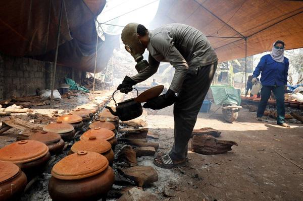 Anh Bùi Văn Cường đeo mặt nạ phòng
độc để kho cá trắm đen trong các niêu đất đặt trên bếp củi. Đây là
một món ăn truyền thống của Việt Nam. Hình ảnh kho cá như vậy
thường xuất hiện ở làng kho cá Vũ Đại, tỉnh Hà Nam, Việt Nam. Ảnh:
Kham/ Reuters