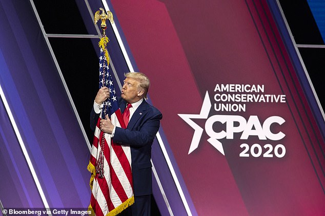 Ông Trump ôm lá cờ Mỹ trong hội nghị CPAC vào năm 2020.