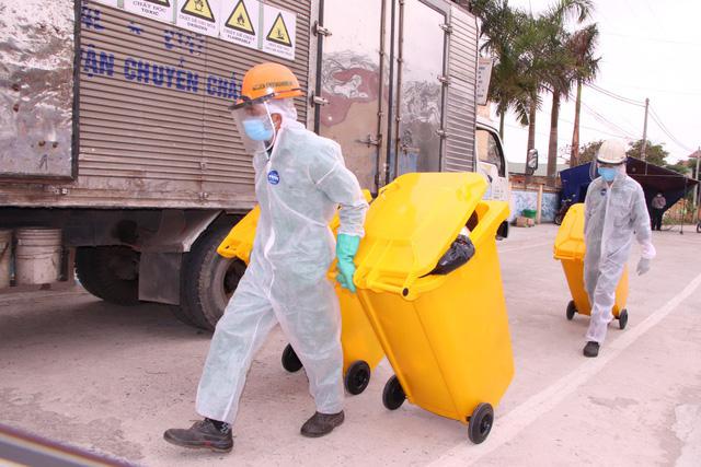 Các công nhân vận chuyển rác thải nguy hiểm từ khu cách ly thuộc trường Tiểu học Lai Cách.