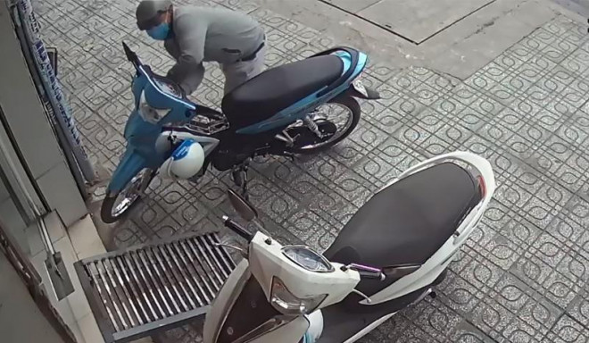 Tên trộm tiếp cận, bẻ khóa chiếc xe máy chỉ trong vài giây rồi phóng đi. Ảnh chụp từ clip