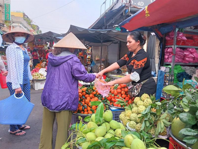 Người dân mua các loại trái cây chuẩn bị cúng ông Táo. ẢNH: TÚ UYÊN