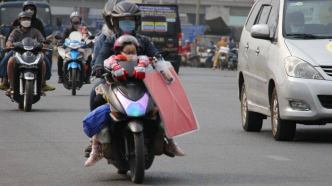 Một gia đình "đèo" nhau trên xe máy với lỉnh kỉnh đồ đạc, hành lý.