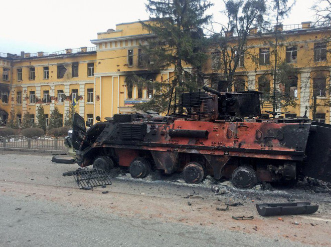 Xe bọc thép bị phá hủy ở Kharkiv, ở phía sau là trường học. Ảnh: Reuters