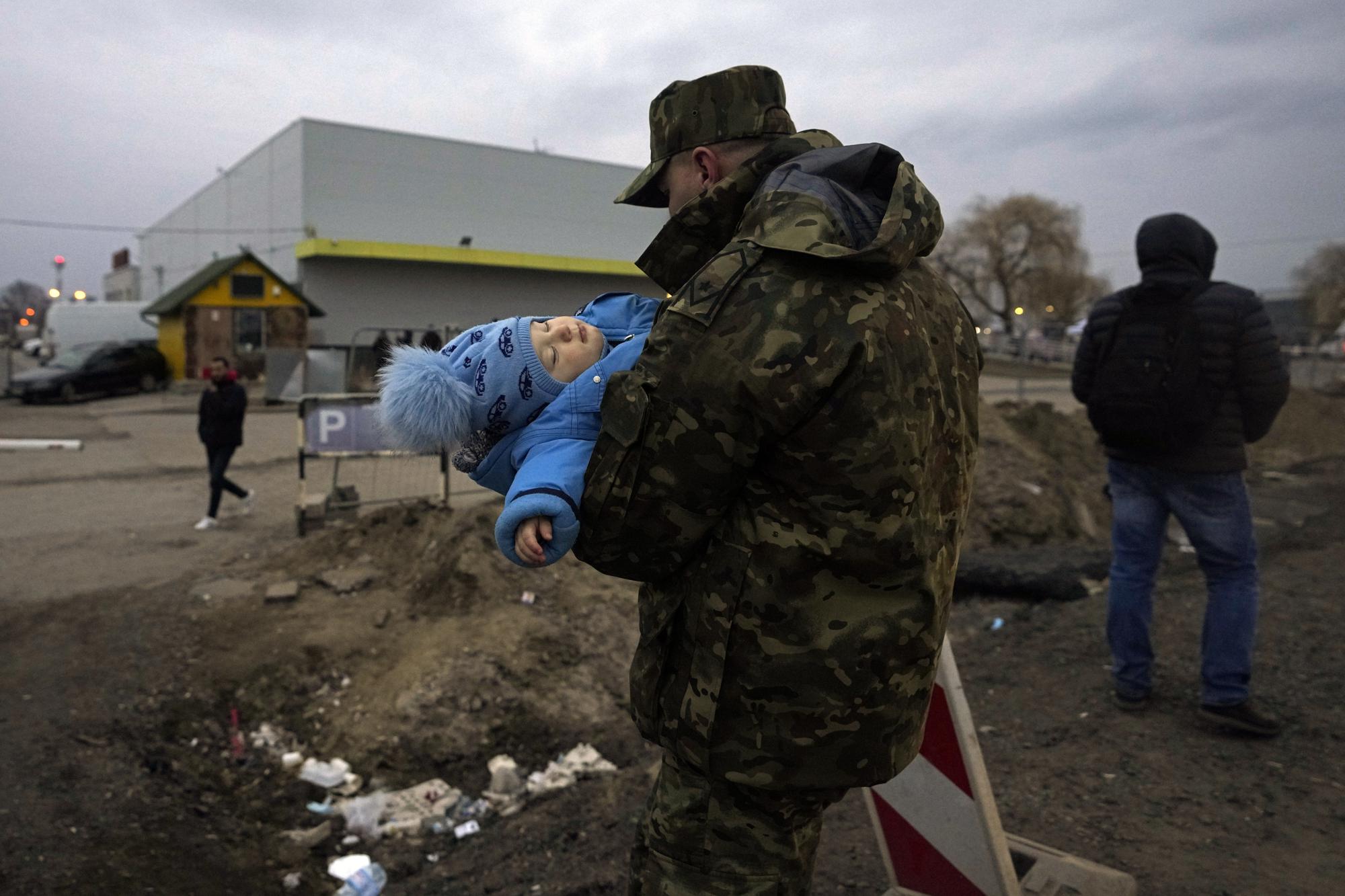 Một binh sĩ Ba Lan bế em bé tị nạn Ukraine khi gia đình em bé tới cửa khẩu biên giới ở Medyka, đông nam Ba Lan, ngày 2/3. Ảnh: AP