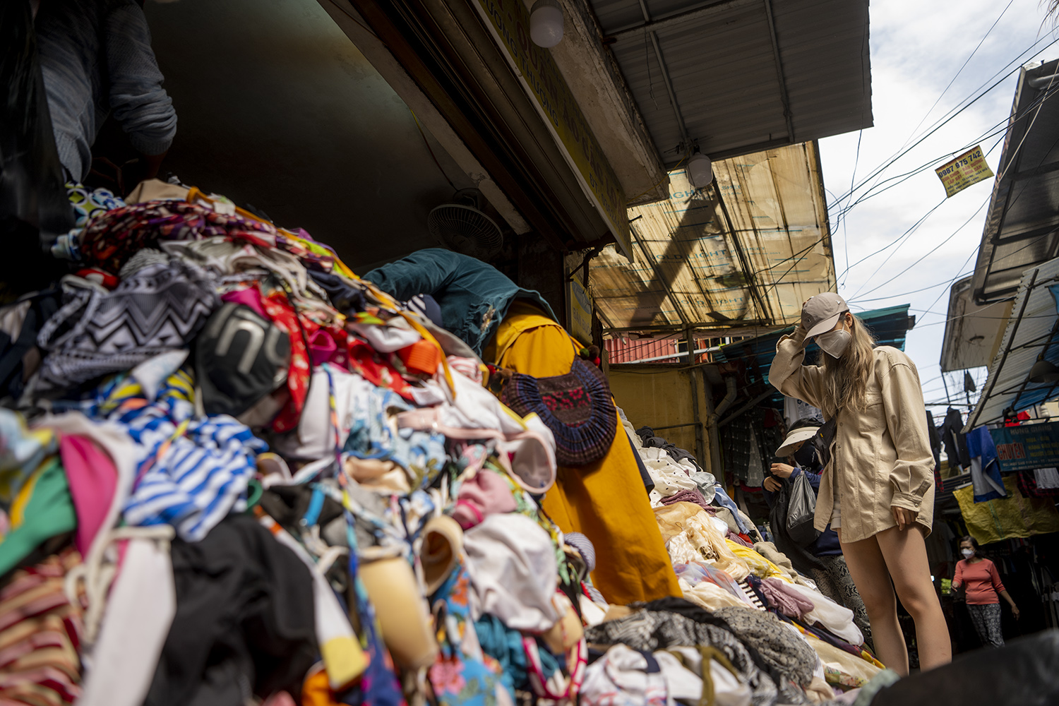 Khi đến khu chợ này, không khó để bắt gặp hình ảnh các bạn trẻ đang lục tìm cho mình những sản phẩm hàng thùng trong các bãi quần áo được chất đống.