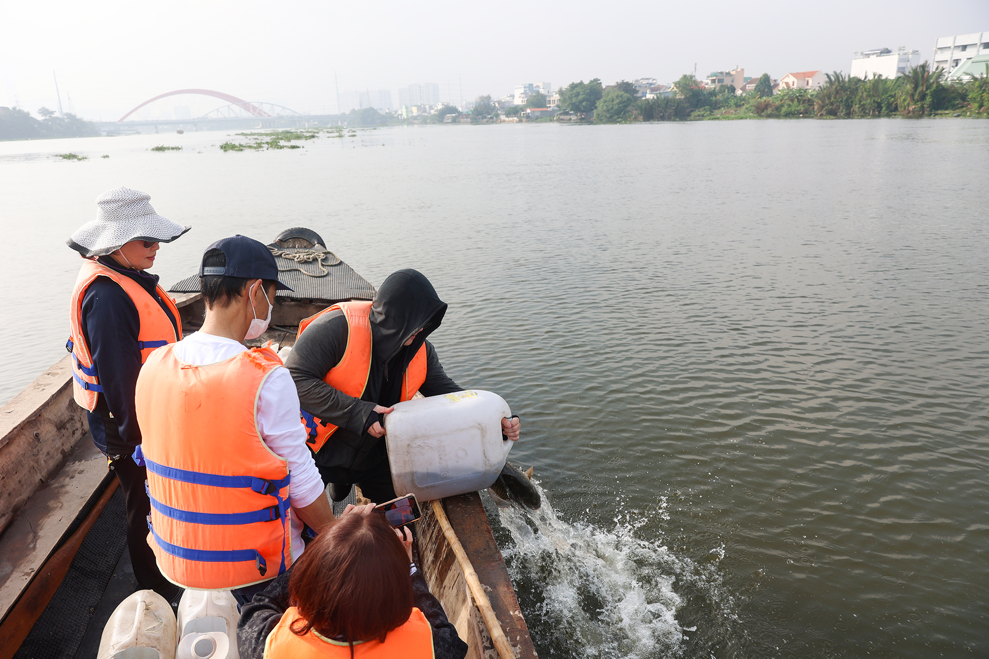 Nhóm người phóng sinh mang hàng chục ký các loại cá ra giữa sông thả, trong đó có những con cá chép trọng lượng đến vài ký.