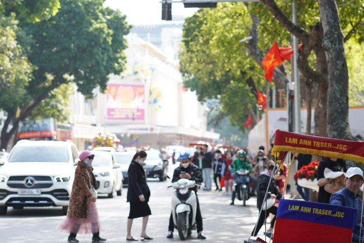 Mặt Hồ Gươm phía Bưu điện Hà Nội đông đúc người, nhiều người dân thong dong di chuyển dưới lòng đường.