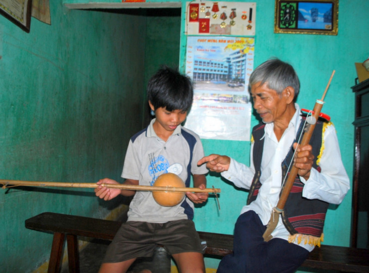 Già làng Nguyễn Văn Cần đang hướng dẫn lớp trẻ chơi nhạc cụ truyền thống Cơ Tu.