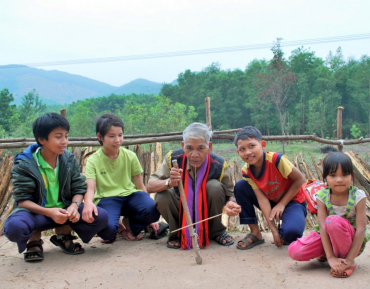 Trẻ em Cơ Tu đang nghe già làng Nguyễn Văn Cần chơi đàn H’roa.