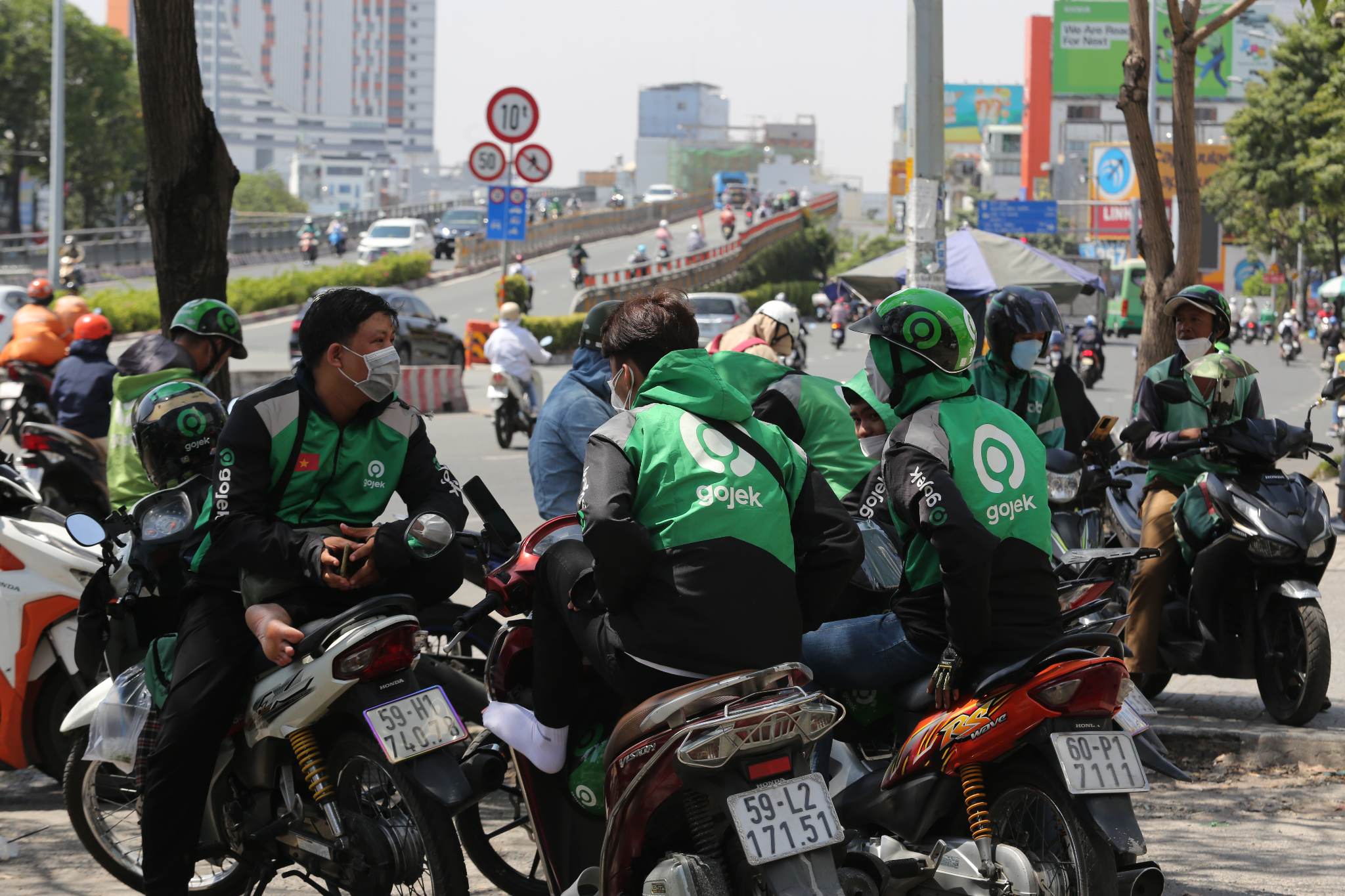 Nhiều người tìm chọn các khu vực có cây xanh, dưới chân cầu vượt để trốn nắng. Anh Nguyễn Hoàng (ngụ TP Thủ Đức) cho biết, do công việc là chạy xe ôm công nghệ nên mỗi ngày phải di chuyển ngoài đường cả 100km. Để tránh nắng nóng, anh mặc 2 áo khoác, 2 khẩu trang vải dày, kính mát. Ngoài ra, trên xe anh luôn có bình nước trà đá để giải nhiệt. “Cả ngày chạy ngoài đường nên tối về mặt nóng rát, tôi phải lấy nước đá rửa mặt cho mát”, anh Hoàng nói.