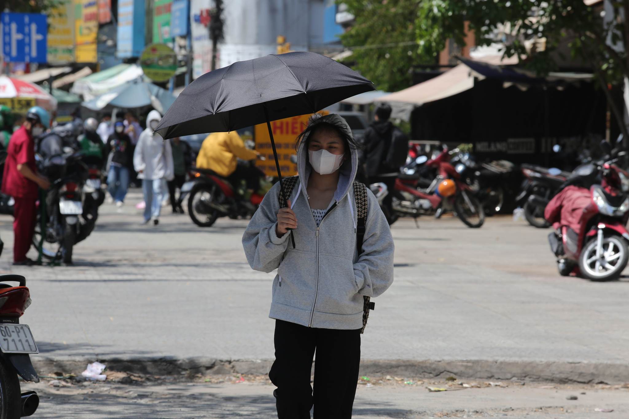 Người dân che dù, mặc áo khoác để chống lại cái nắng rát mặt khi ra đường.