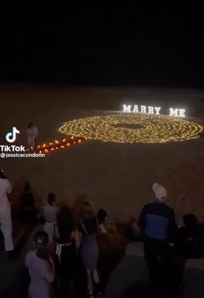 Màn cầu hôn công phu có hàng trăm ngọn nến và tấm biển “Marry Me” khổng lồ được thắp sáng trên cát.