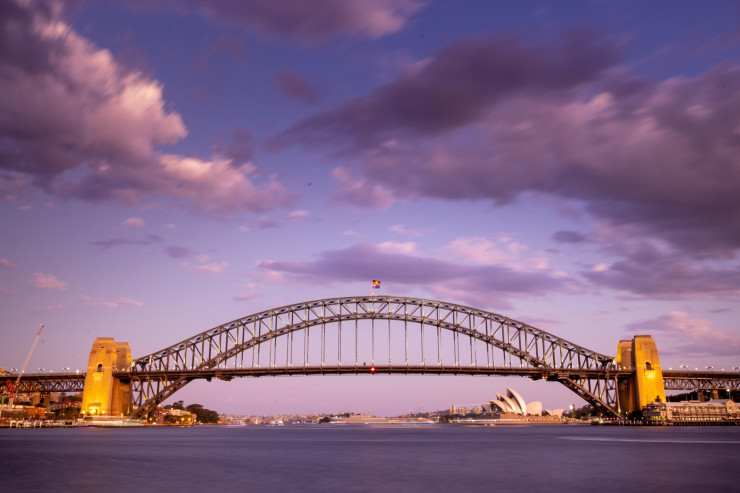 Cầu Cảng Sydney là chiếc cầu thép lớn nhất thế giới, có biệt danh là "Cái móc áo"&nbsp;do kiến trúc vòm của nó. Cây cầu được chính tay kiến trúc sư John Bradfield thiết kế, do công ty Dorman Long xây dựng và khánh thành vào năm 1932. Đứng trên cầu vào buổi chiều, du khách sẽ có tầm nhìn lý tưởng để chiêm ngắm hoàng hôn.