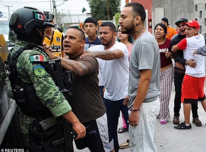 Binh sĩ Mexico bị người dân túm áo chất vấn. Ảnh: Reuters