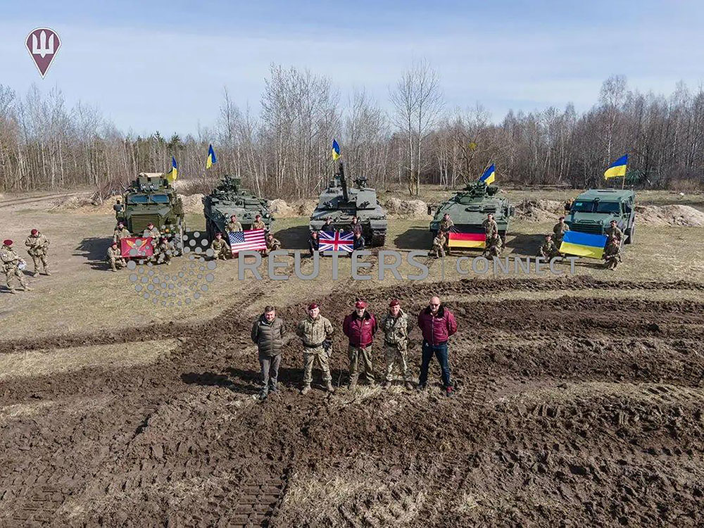 Bộ trưởng Quốc phòng Ukraine đứng cạnh những chiếc xe tăng, xe bọc thép phương Tây mới viện trợ (ảnh: CNN)