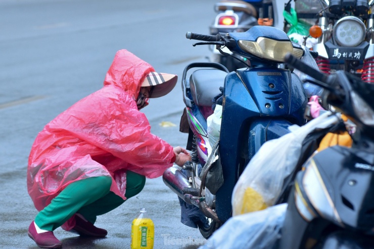 Một người phụ nữ loay hoay sửa xe ngay trên đường.