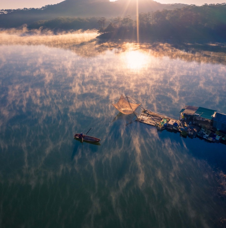 "Lão ngư dân tên Quyền, hơn 70 tuổi, sinh sống nhiều năm trong ngôi nhà nhỏ dựng đơn sơ bên cạnh rừng thông, cùng một chú chó lông trắng. Hàng ngày, ông Quyền mưu sinh bằng chiếc rớ nhỏ, dùng để đánh bắt cá ở lòng hồ Suối Tía, thi thoảng được nhờ làm mẫu chụp hình cho các nhiếp ảnh gia và chèo đò cho khách tham quan", anh Hải hồi tưởng về hình ảnh ông lão đánh cá. Ảnh: Bùi Văn Hải.