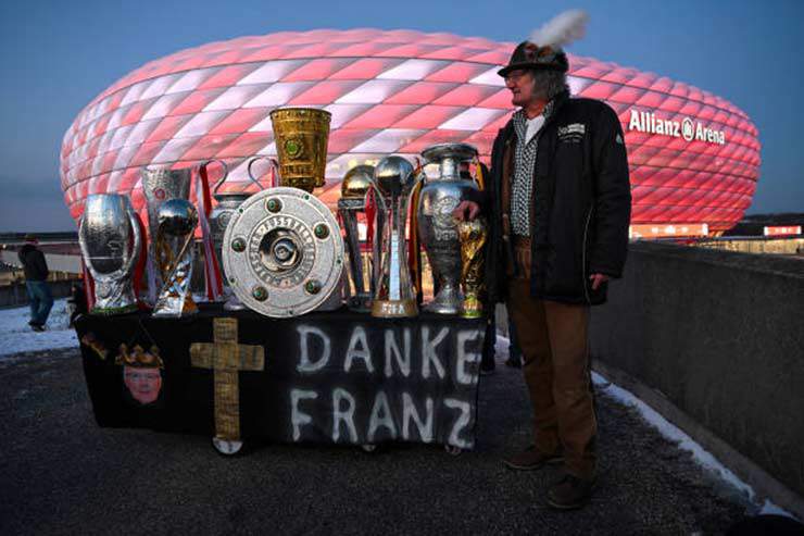 Một fan Bayern bên ngoài sân với phiên bản sao chép của những chiếc cúp Beckenbauer đã giành được